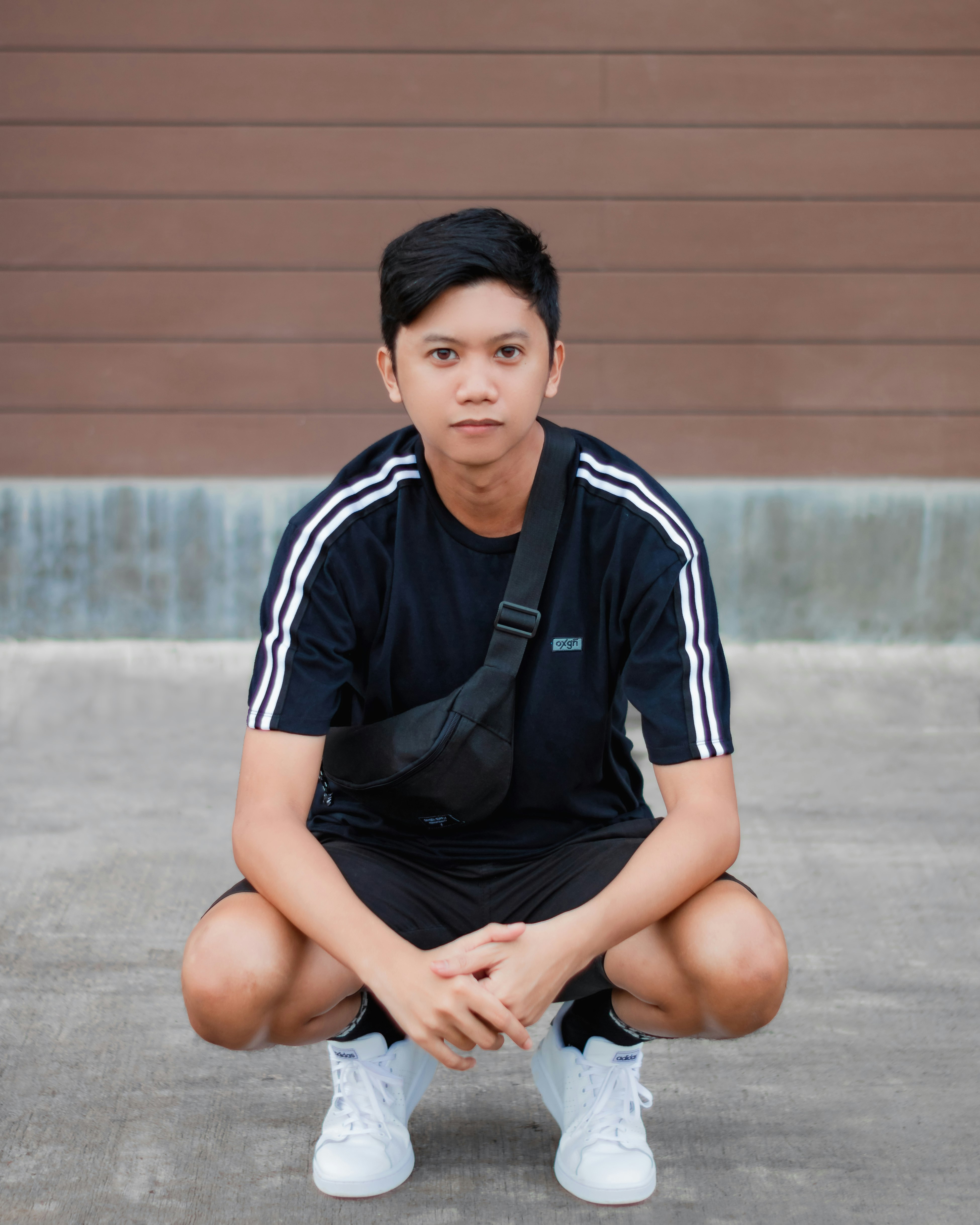 man squatting on concrete pavement